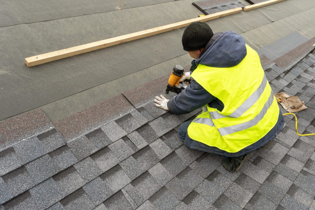 Roofer installing new shingles on a residential roof